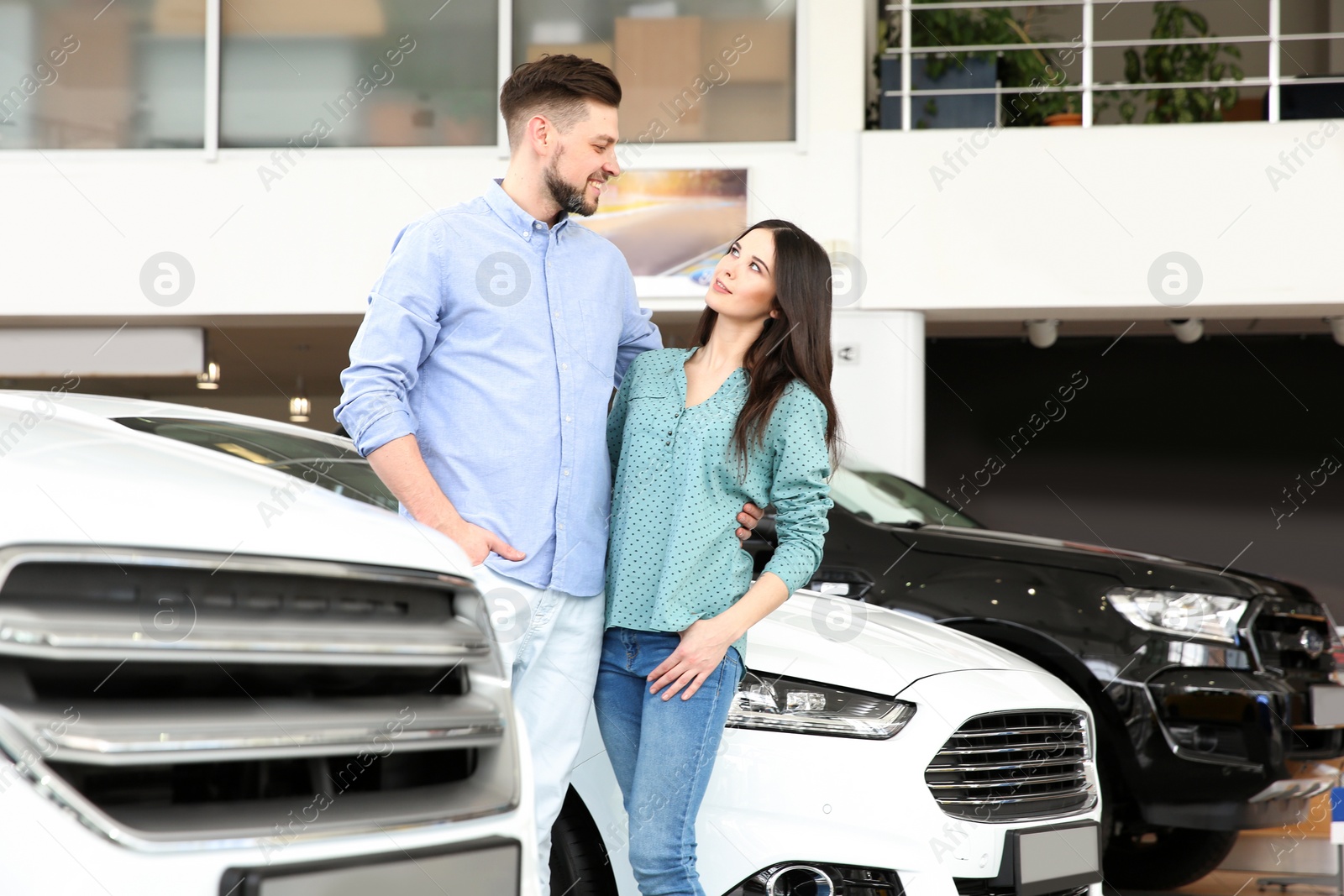 Photo of Young couple buying new car in salon