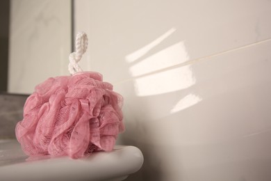 Photo of Pink shower puff on washbasin in bathroom, closeup. Space for text