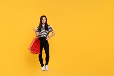 Photo of Beautiful woman with shopping bags on yellow background. Space for text