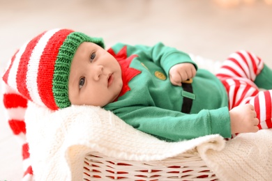 Photo of Cute baby wearing Christmas costume lying in basket at home