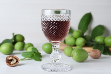 Photo of Delicious liqueur and fresh walnuts on white wooden table