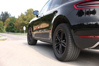 Modern black car parked on asphalt road outdoors