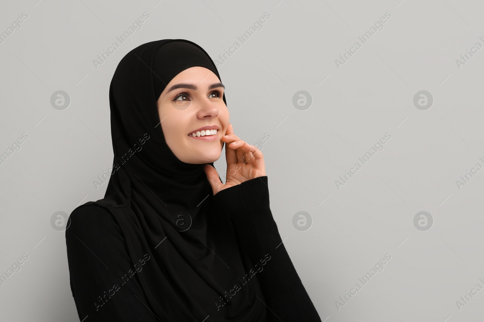 Photo of Portrait of Muslim woman in hijab on light gray background, space for text