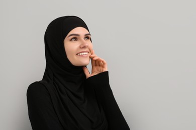 Portrait of Muslim woman in hijab on light gray background, space for text