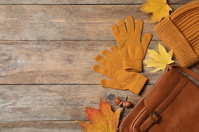 Photo of Flat lay composition with stylish orange woolen gloves and dry leaves on wooden table. Space for text