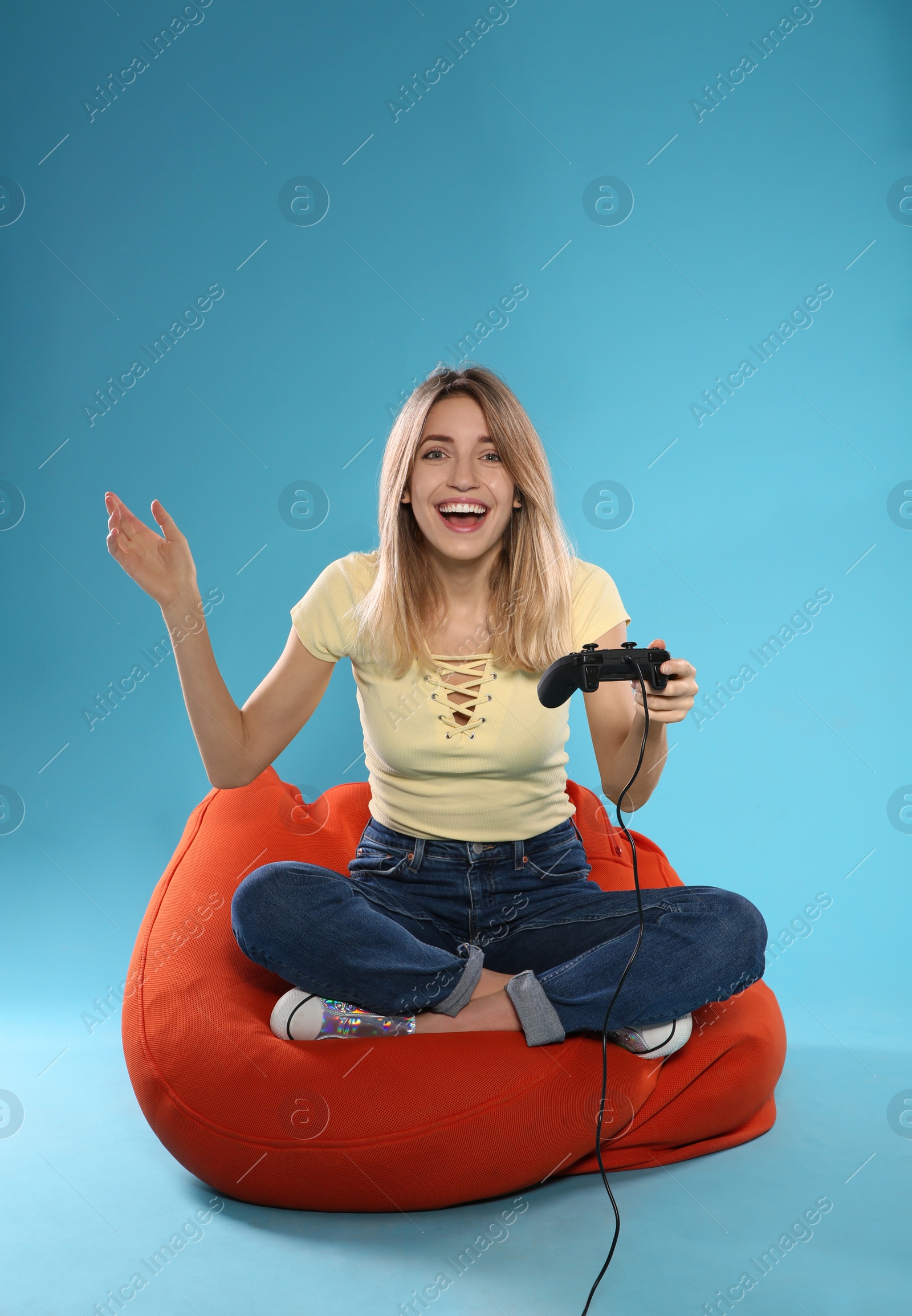 Photo of Emotional young woman playing video games with controller on color background. Space for text