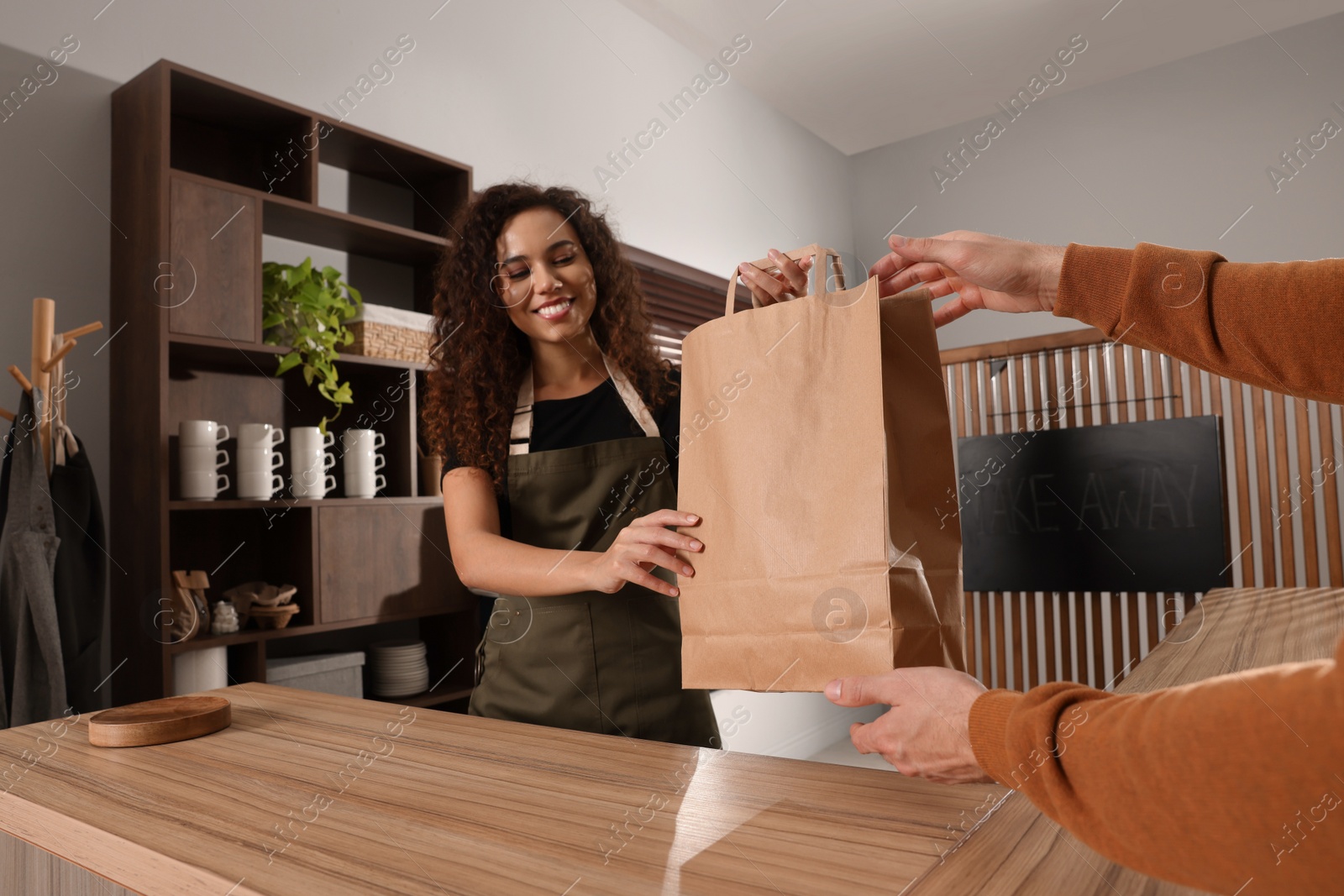 Photo of Worker giving paper bag to customer in cafe