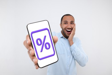 Discount, offer, sale. Emotional man showing mobile phone with percent sign on screen, white background