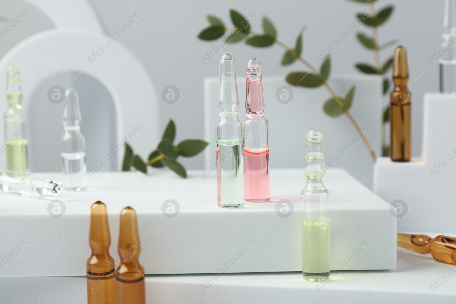 Photo of Stylish presentation of different skincare ampoules on white background, closeup