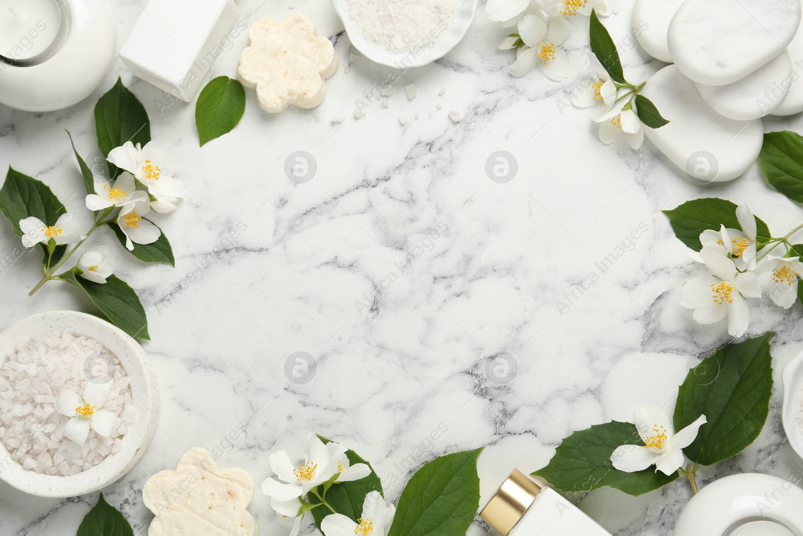 Photo of Jasmine flowers and set of spa essentials on white marble table, flat lay. Space for text