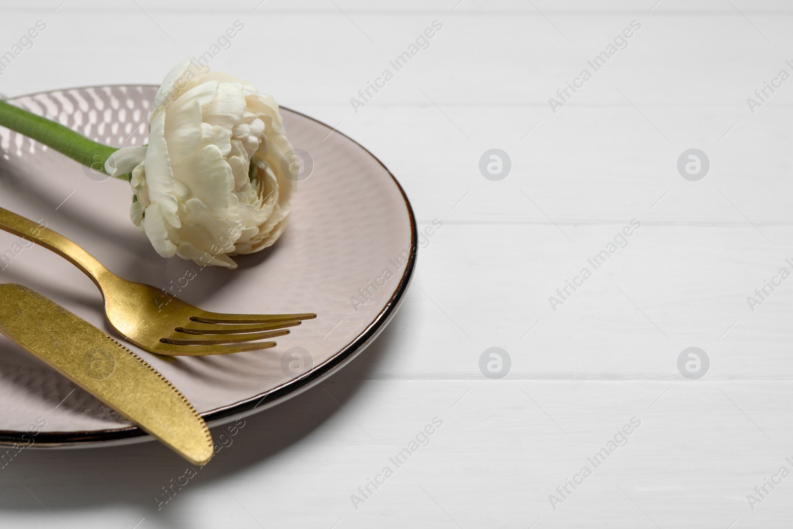 Photo of Stylish table setting with cutlery and flower on white wooden background, closeup. Space for text