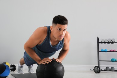 Photo of Athletic man doing push ups with medicine ball in modern gym, space for text