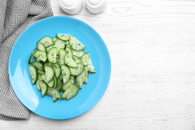 Plate of tasty cucumber salad served on white wooden table, flat lay. Space for text