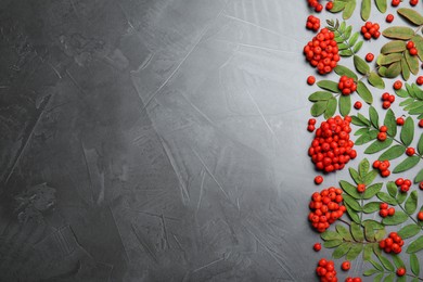 Photo of Fresh ripe rowan berries and green leaves on grey table, flat lay. Space for text