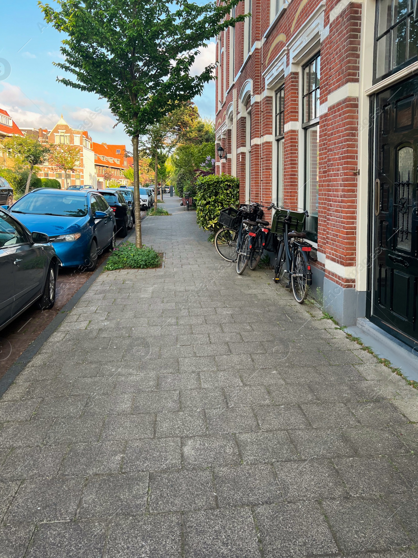 Photo of Beautiful view of city street with modern houses, bicycles and parked cars