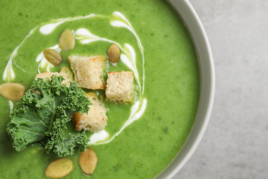 Photo of Tasty kale soup with croutons on grey table, closeup