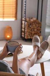 Woman with cup of aromatic coffee relaxing at home, closeup