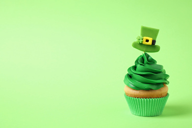 Photo of Delicious decorated cupcake on light green background, space for text. St. Patrick's Day celebration