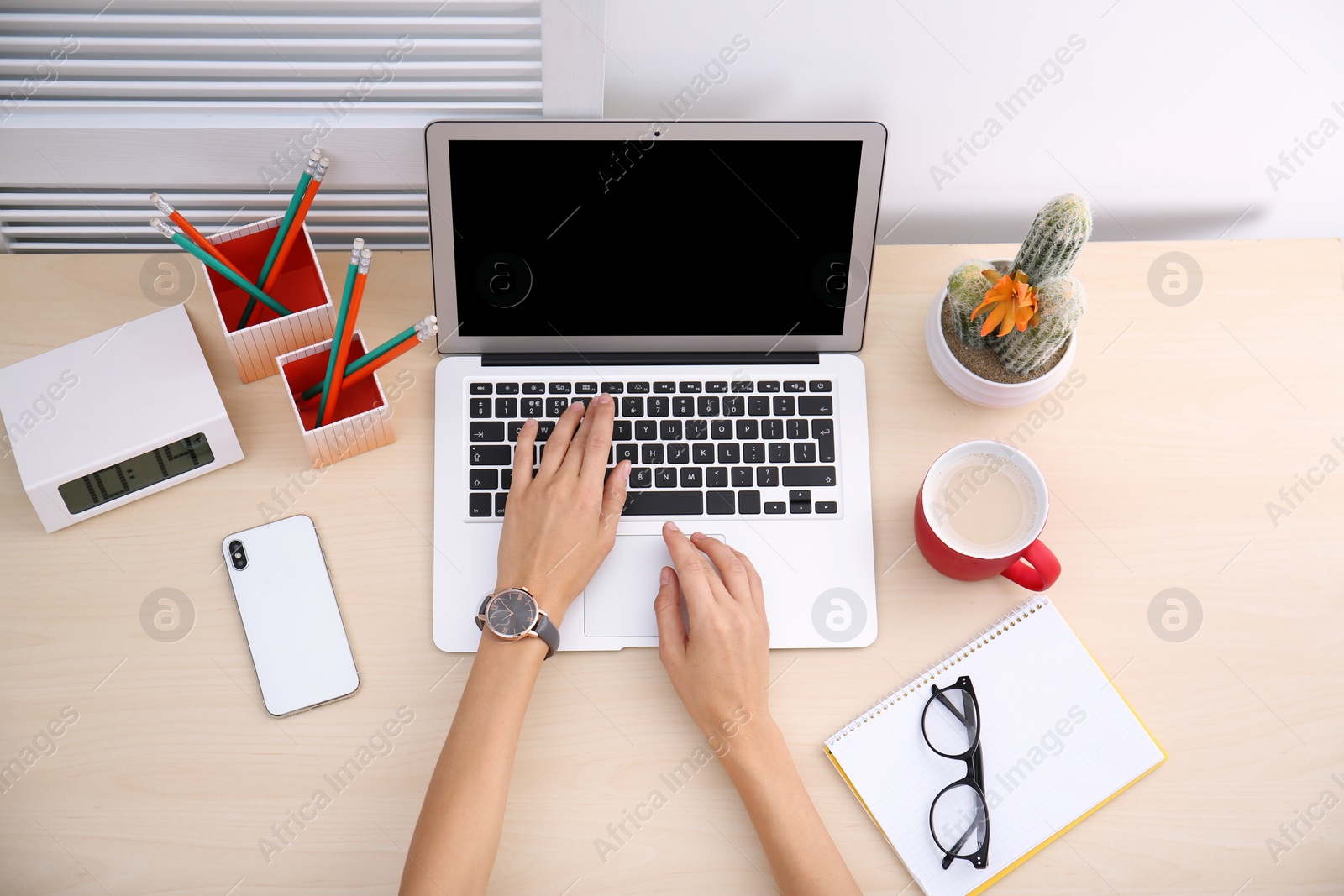 Photo of Female blogger using laptop at table, top view. Blank screen for mockup