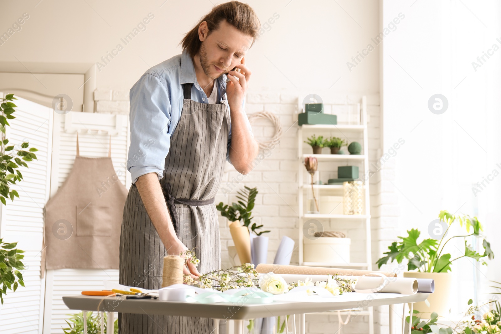 Photo of Male florist talking on phone at workplace