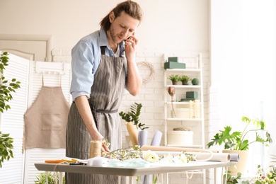 Photo of Male florist talking on phone at workplace