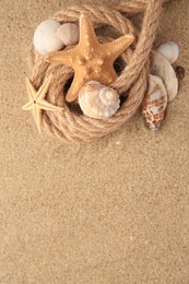 Beautiful sea stars, shells and rope on sand, flat lay. Space for text