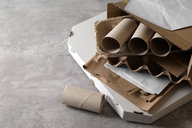 Photo of Stack of different waste paper on grey table, closeup. Space for text