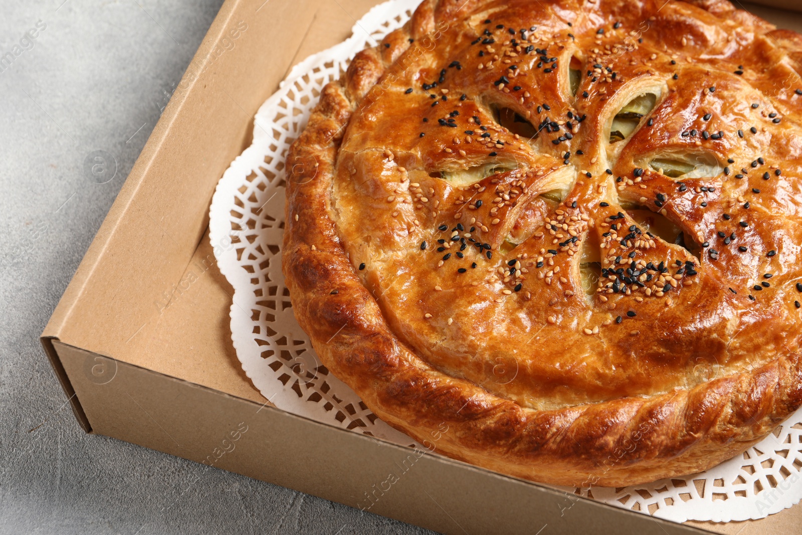 Photo of Tasty homemade pie in box on light table, closeup