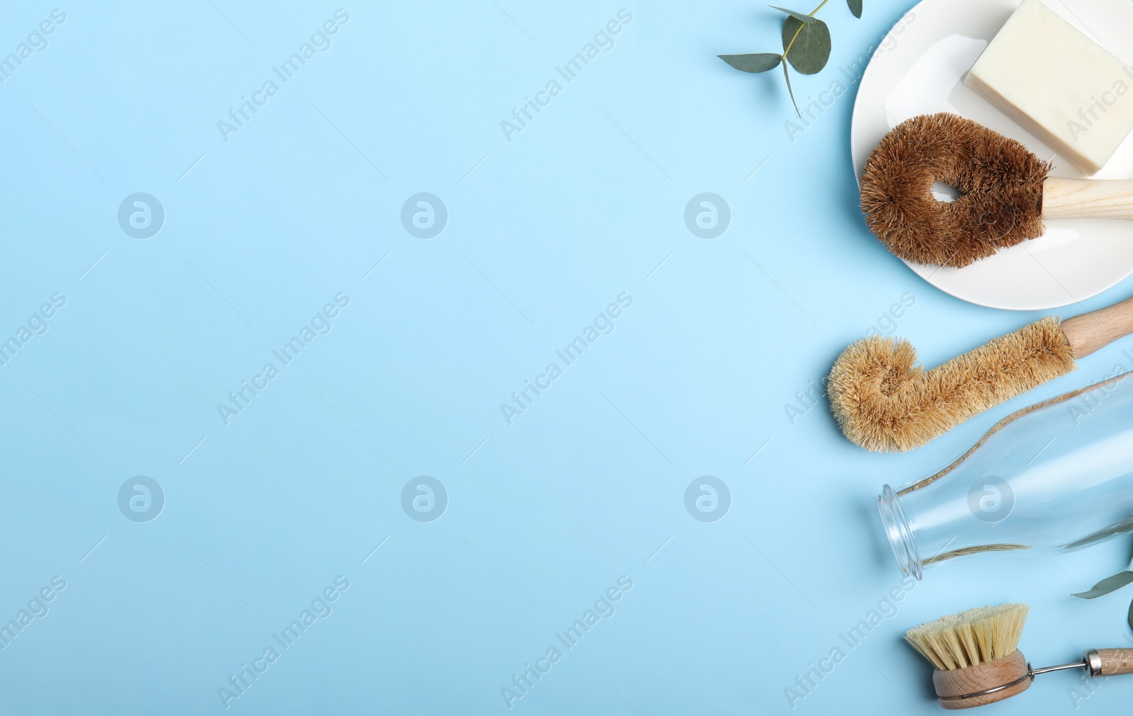 Photo of Flat lay composition with cleaning tools on light blue background, space for text. Dish washing supplies