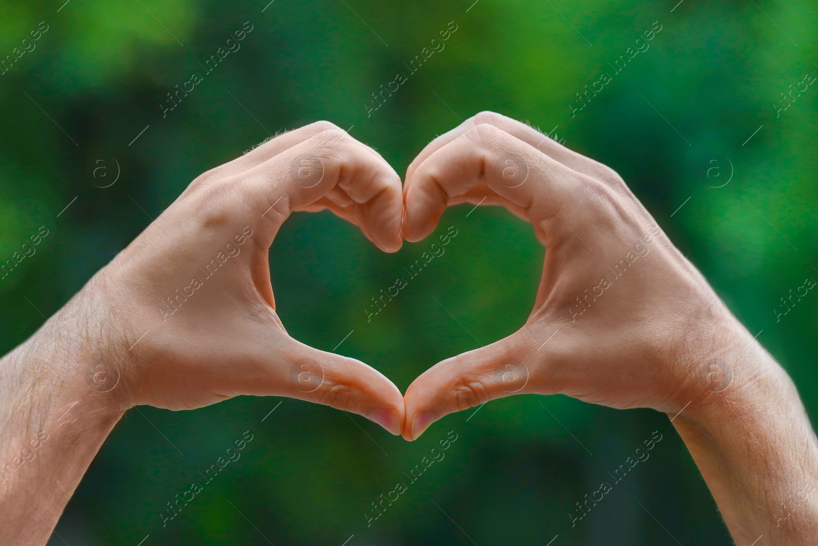 Photo of Man making heart with hands outdoors, closeup