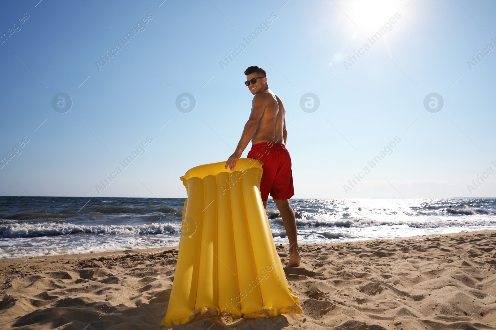 Photo of Man with yellow inflatable mattress at beach