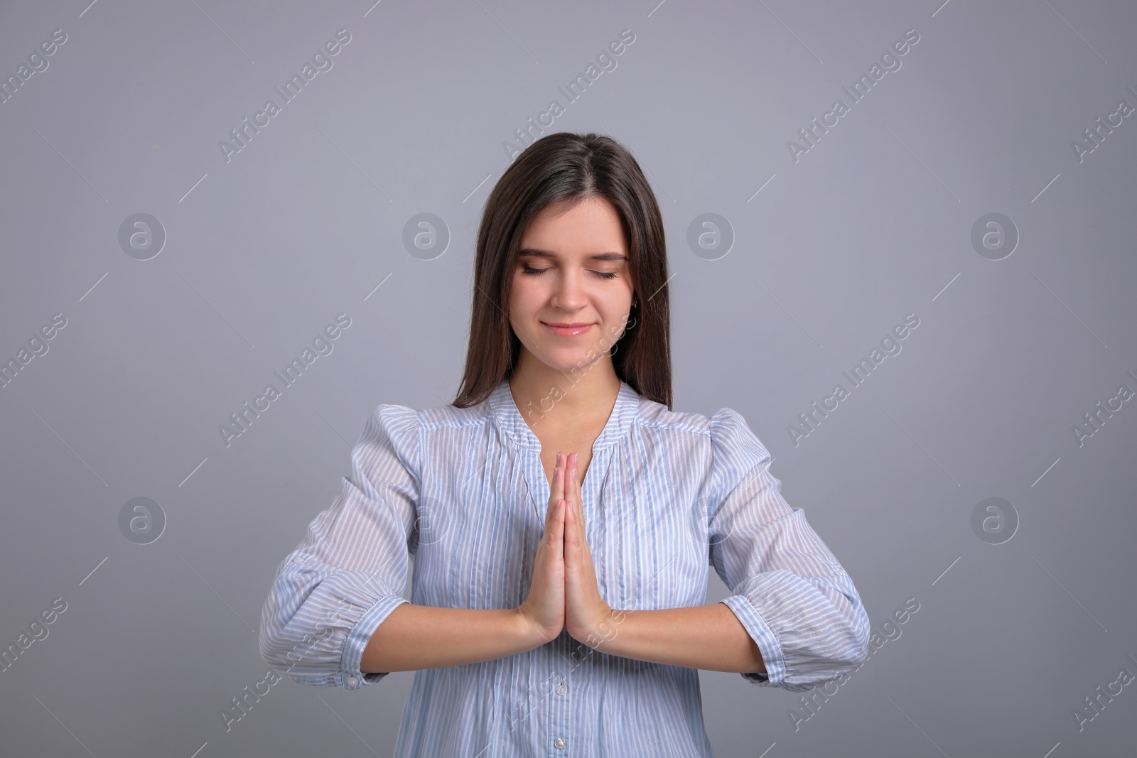 Photo of Young woman meditating on grey background. Stress relief exercise