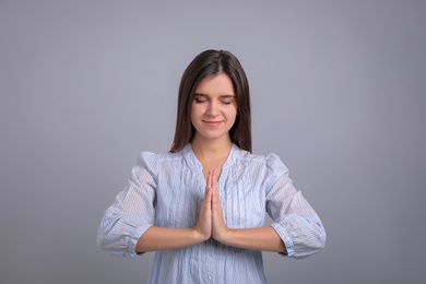 Young woman meditating on grey background. Stress relief exercise