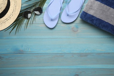 Photo of Beach towel, straw hat, flip flops and sunglasses on light blue wooden background, flat lay. Space for text