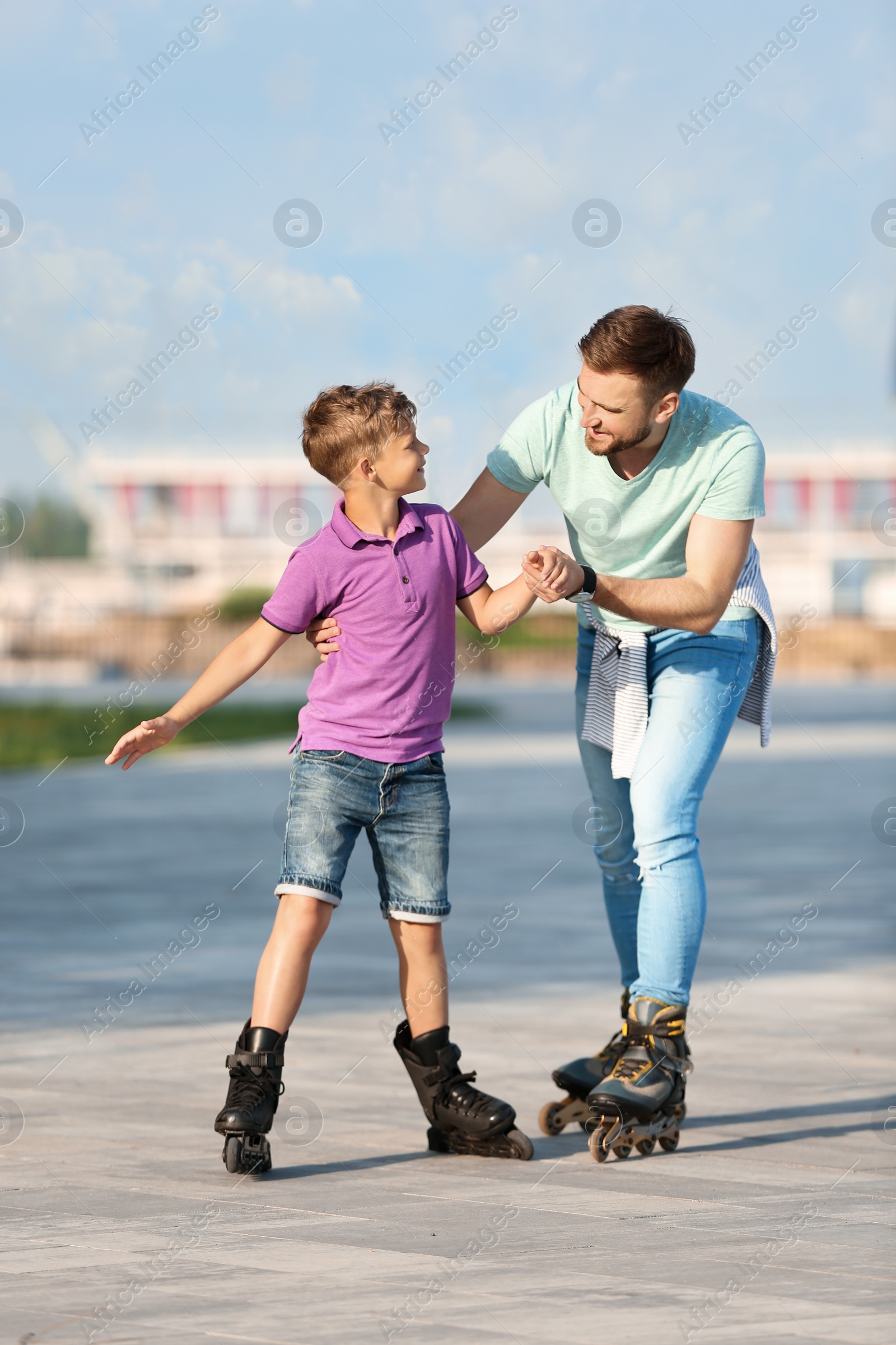 Photo of Father and son roller skating on city street