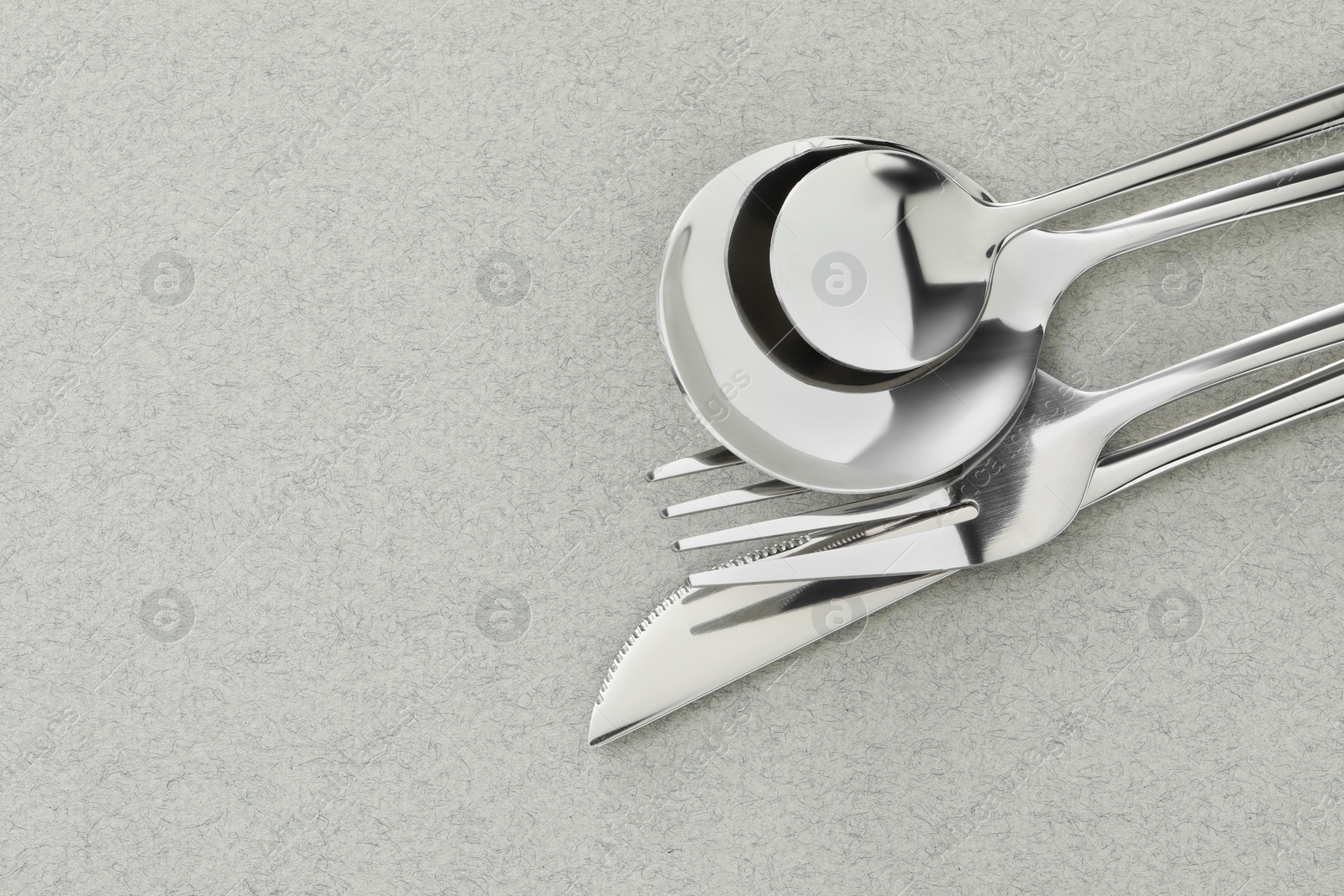Photo of Fork, knife and spoons on grey background, flat lay with space for text. Stylish cutlery set