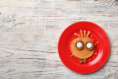 Funny pancake for kids breakfast on wooden table, top view