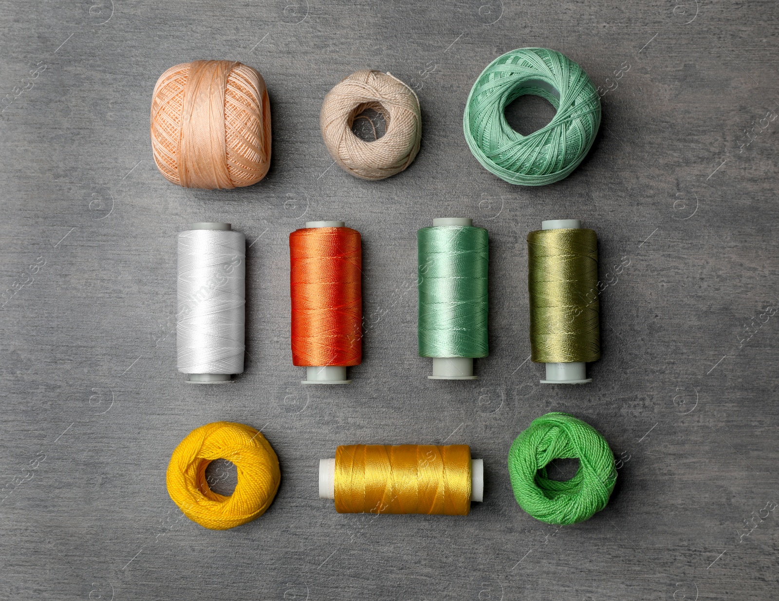 Photo of Color sewing threads on gray background, top view