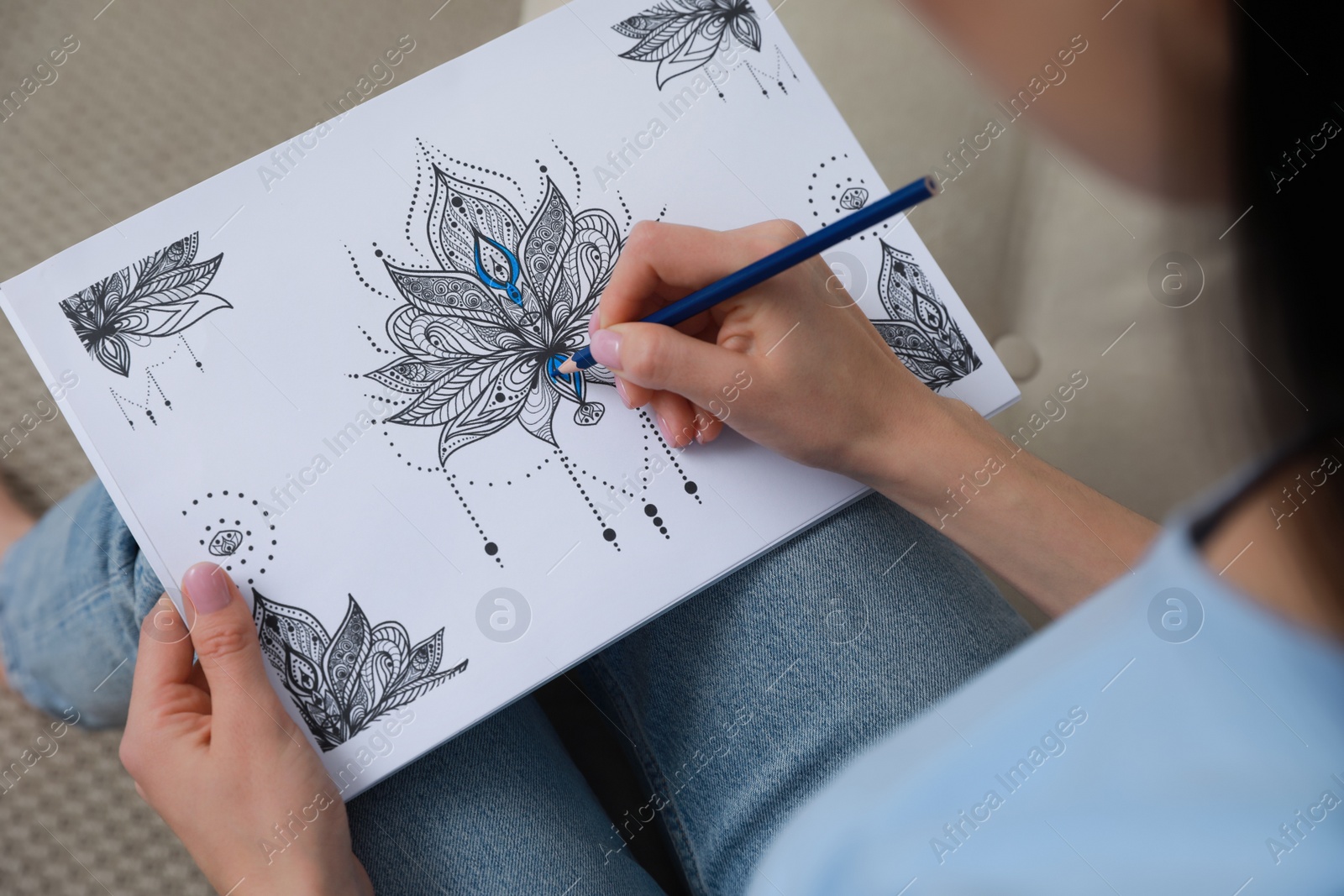 Photo of Young woman coloring antistress page on sofa, closeup