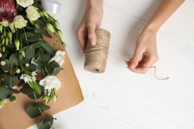 Florist making beautiful bouquet at white wooden table, top view