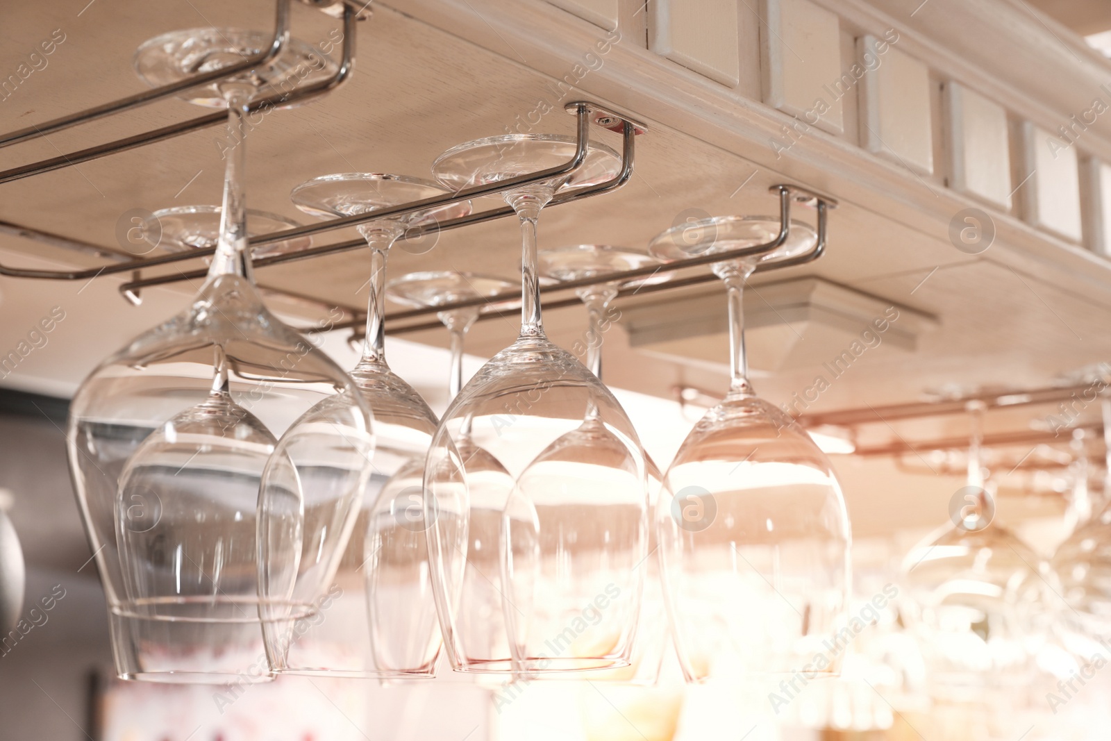 Photo of Set of empty clean glasses on bar racks