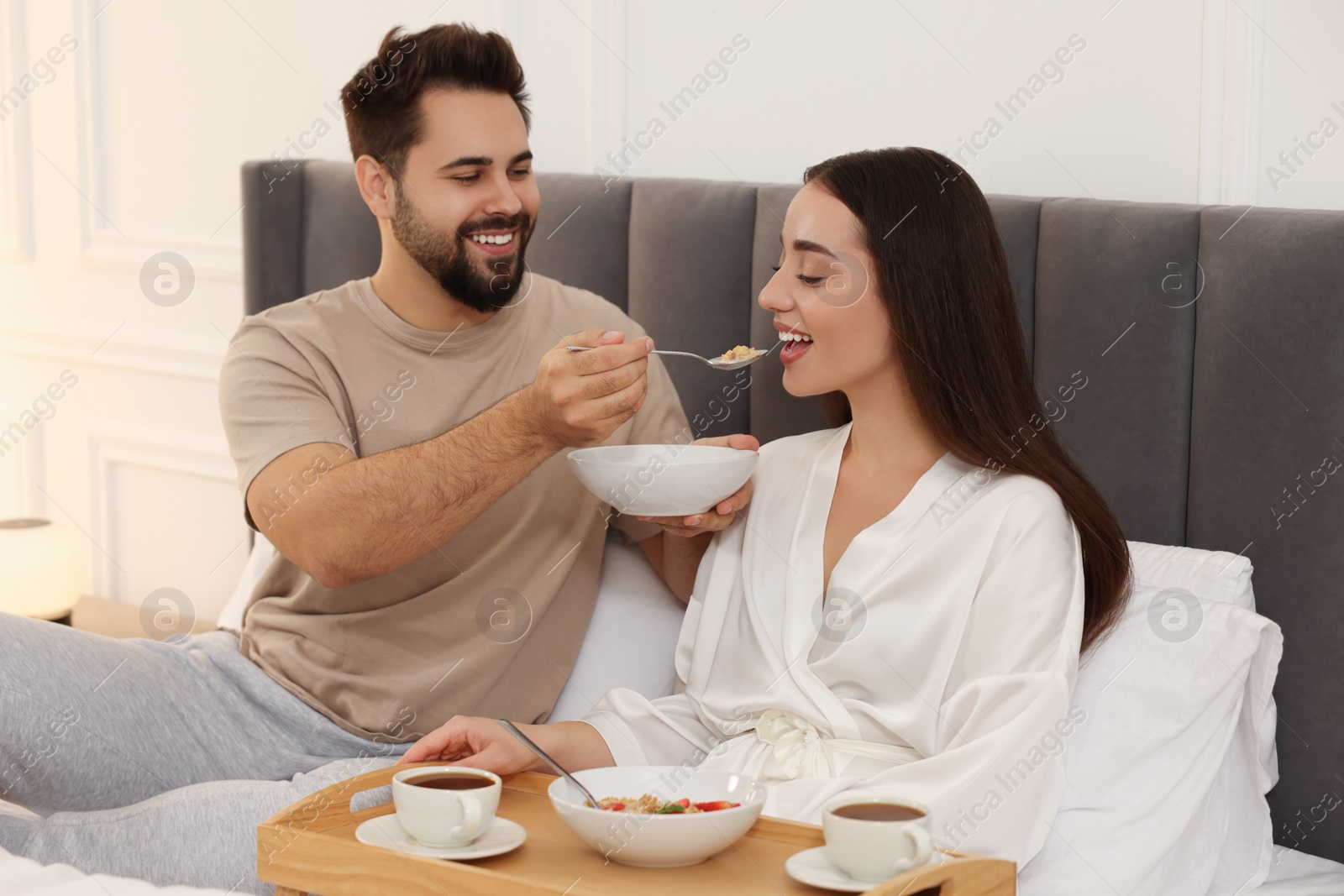 Photo of Happy couple having breakfast on bed at home