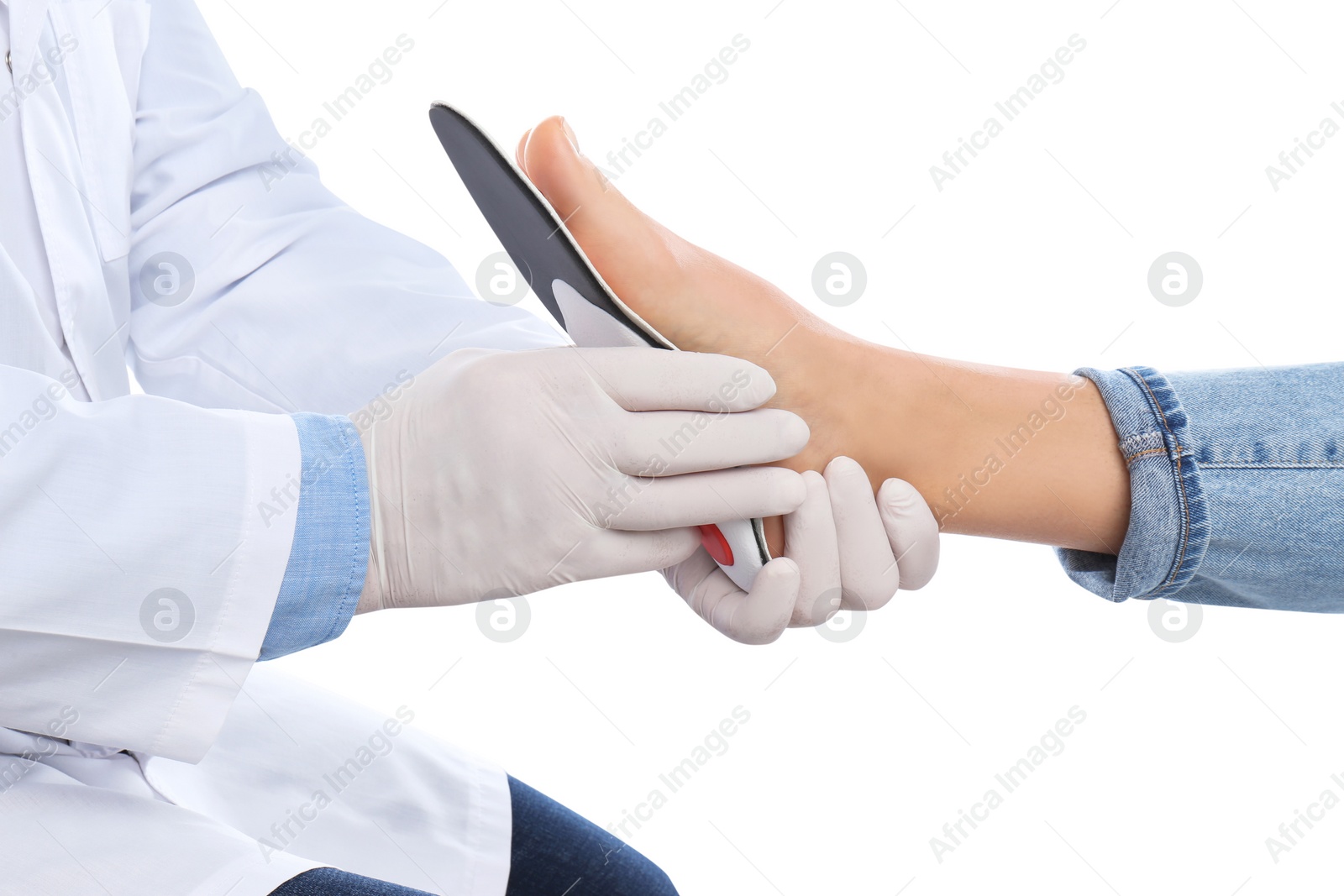 Photo of Male orthopedist fitting insole on patient's foot against white background, closeup