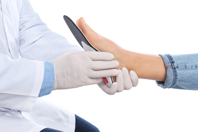 Male orthopedist fitting insole on patient's foot against white background, closeup