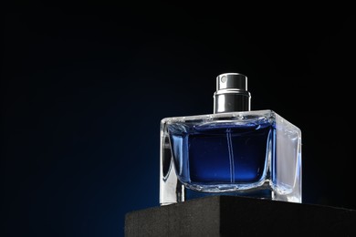 Luxury men`s perfume in bottle against dark background, low angle view. Space for text