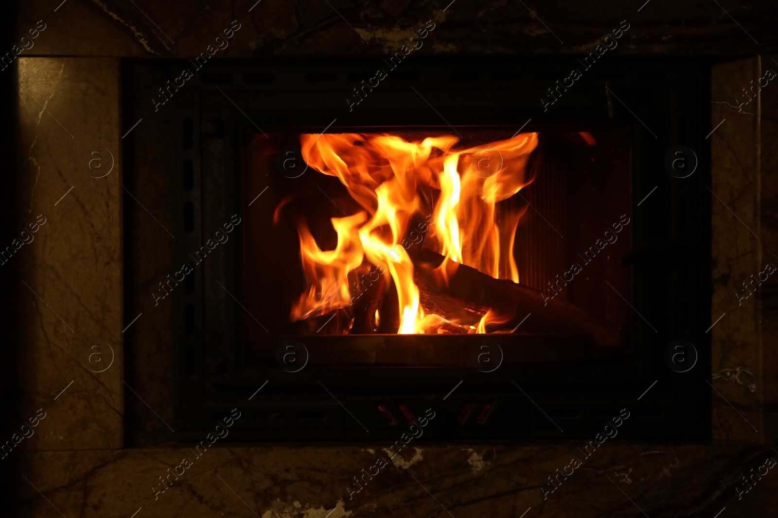 Photo of Fireplace with burning wood in darkness indoors