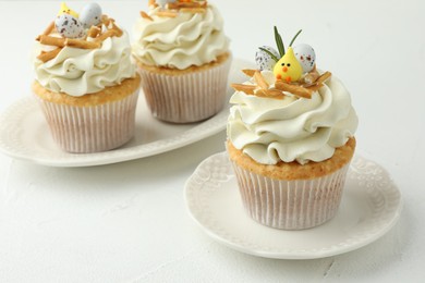 Photo of Tasty Easter cupcakes with vanilla cream on white table, closeup