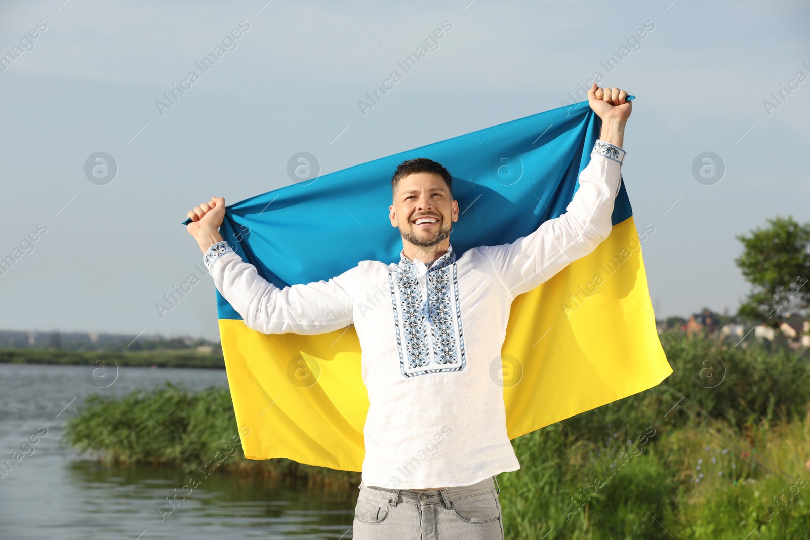 Photo of Man in vyshyvanka with flag of Ukraine outdoors