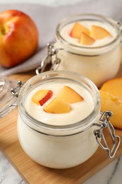 Photo of Delicious yogurt with fresh peach on white table, closeup