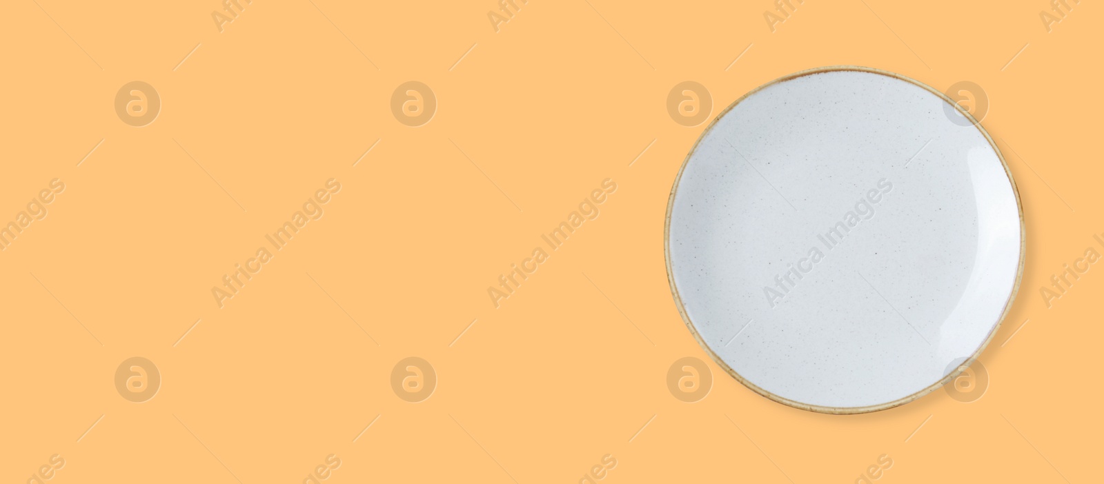 Image of Empty white ceramic plate on pale orange background, top view and space for text. Banner design